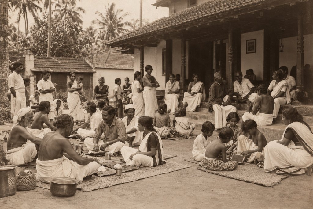 Kerala community gathered peacefully in a traditional heritage courtyard enjoying community meal and fellowship